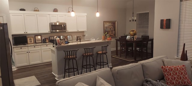 kitchen featuring pendant lighting, dark hardwood / wood-style floors, light stone counters, white cabinetry, and stainless steel appliances