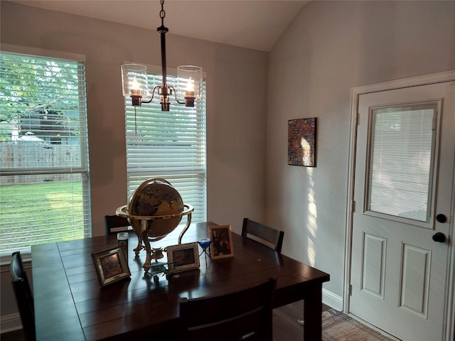 dining area with a chandelier, vaulted ceiling, and wood-type flooring