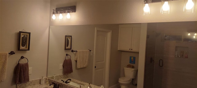 bathroom featuring toilet, a shower with shower door, and sink