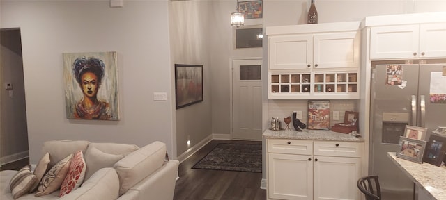 kitchen with light stone countertops, stainless steel fridge with ice dispenser, white cabinets, and pendant lighting