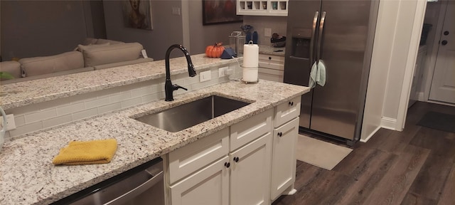 kitchen with light stone counters, sink, white cabinets, and stainless steel appliances