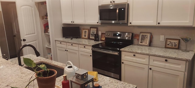 kitchen featuring tasteful backsplash, light stone counters, white cabinetry, and stainless steel appliances