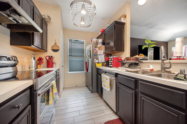 kitchen with dark brown cabinets, stainless steel appliances, light wood-type flooring, wall chimney exhaust hood, and sink