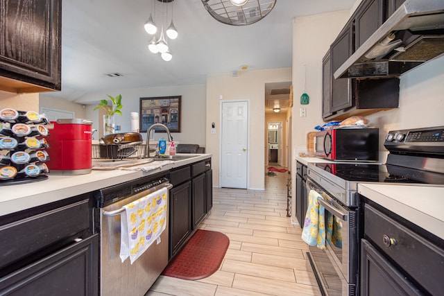 kitchen with wall chimney range hood, stainless steel appliances, dark brown cabinets, sink, and pendant lighting