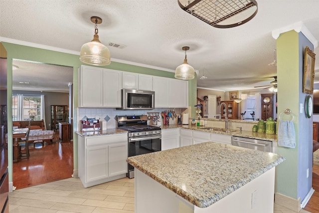 kitchen featuring white cabinetry, kitchen peninsula, stainless steel appliances, and hanging light fixtures