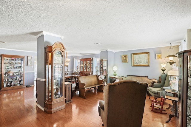 living room with a textured ceiling, hardwood / wood-style flooring, and ornamental molding