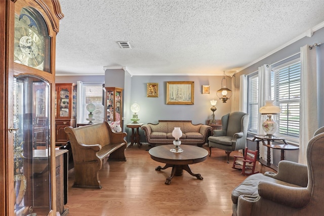 living room featuring a textured ceiling, light wood-type flooring, and crown molding