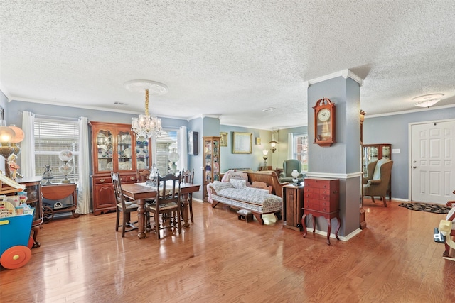 dining room featuring a chandelier, crown molding, a healthy amount of sunlight, and light wood-type flooring