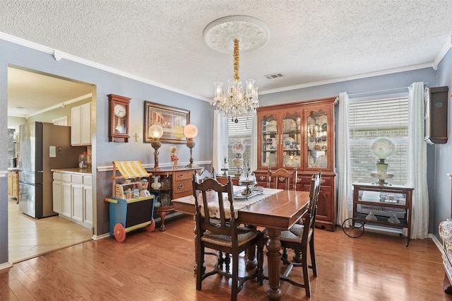 dining area with a chandelier, a healthy amount of sunlight, light wood-type flooring, and ornamental molding