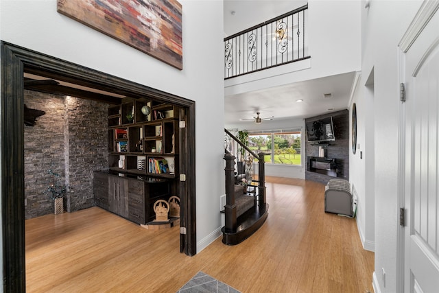 foyer with a towering ceiling, ceiling fan, and light hardwood / wood-style floors