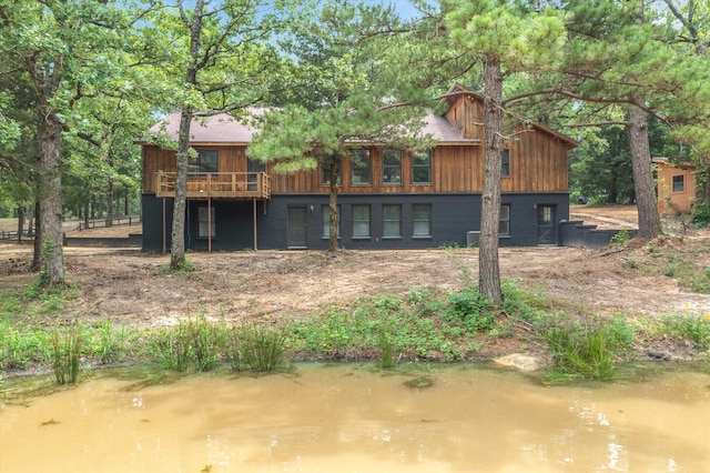 back of property featuring a deck with water view