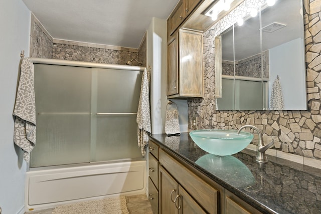 bathroom featuring decorative backsplash, vanity, and combined bath / shower with glass door