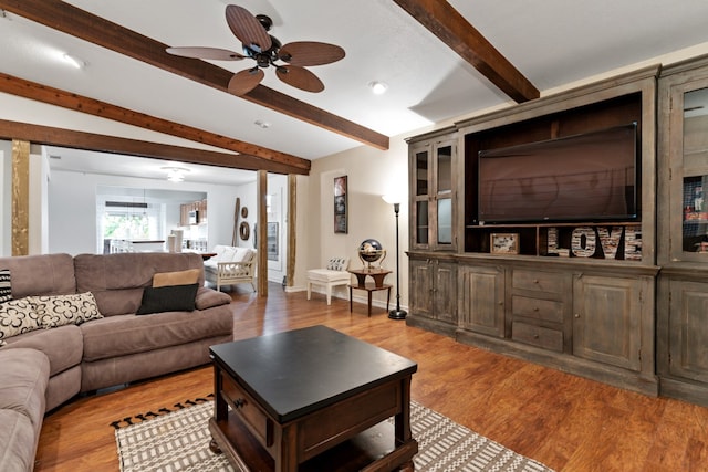 living room featuring ceiling fan, beam ceiling, and light wood-type flooring