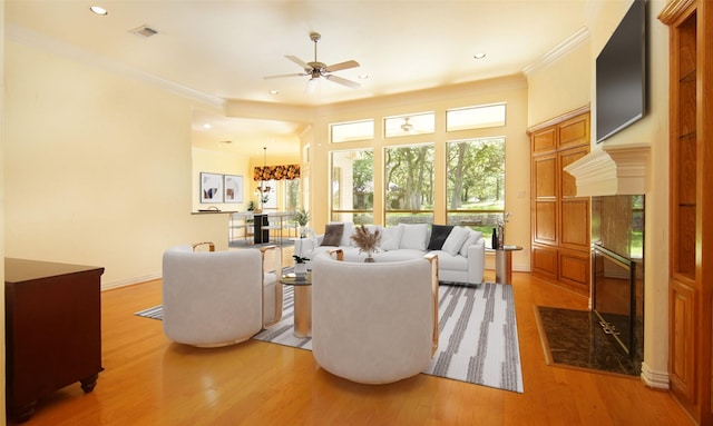 living room with hardwood / wood-style floors, ceiling fan, and crown molding