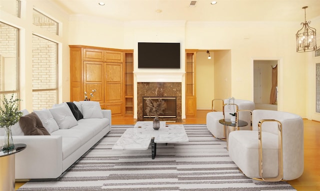 living room with light wood-type flooring, crown molding, and a tiled fireplace