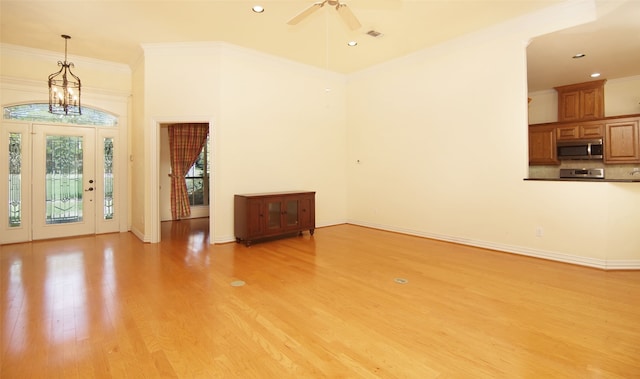 unfurnished living room with light hardwood / wood-style flooring, ceiling fan with notable chandelier, and ornamental molding