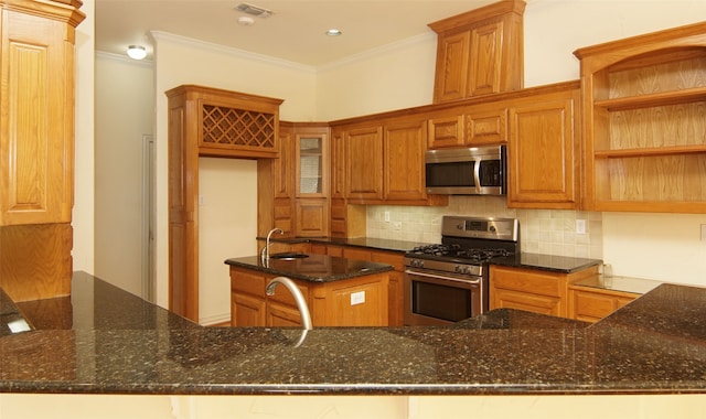 kitchen with kitchen peninsula, ornamental molding, dark stone counters, and appliances with stainless steel finishes