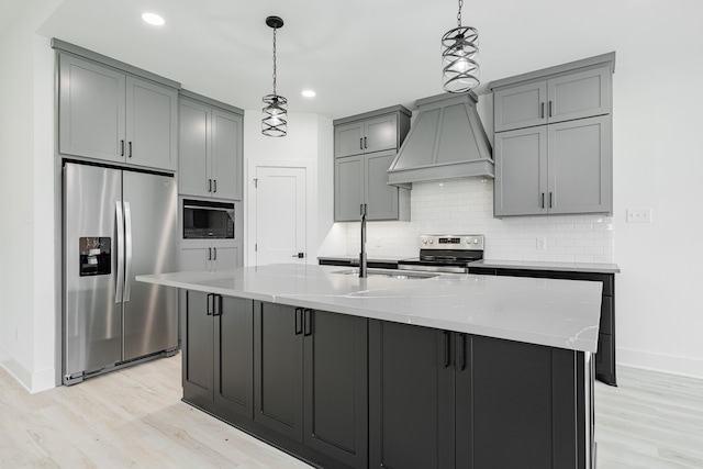 kitchen featuring decorative light fixtures, light stone counters, custom range hood, light wood-type flooring, and appliances with stainless steel finishes