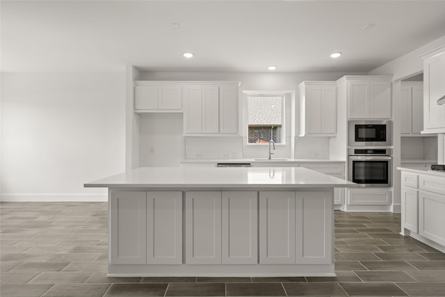 kitchen with stainless steel oven, a center island, sink, and black microwave