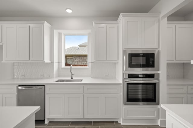 kitchen featuring sink, stainless steel appliances, decorative backsplash, and white cabinetry