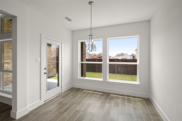 unfurnished dining area featuring dark wood-type flooring and a chandelier