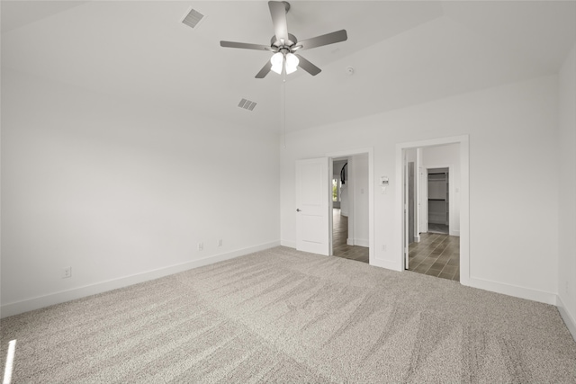 unfurnished bedroom with a walk in closet, carpet, high vaulted ceiling, a closet, and ceiling fan