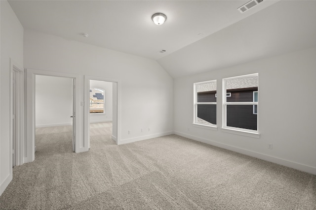 unfurnished bedroom featuring vaulted ceiling and light carpet