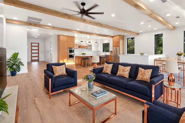 living room with ceiling fan, light wood-type flooring, and beam ceiling