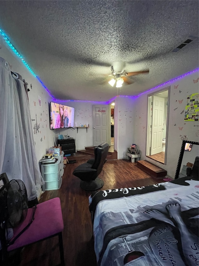 bedroom with a textured ceiling, wood-type flooring, and ceiling fan