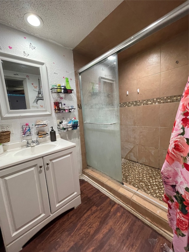 bathroom with an enclosed shower, a textured ceiling, hardwood / wood-style floors, and vanity