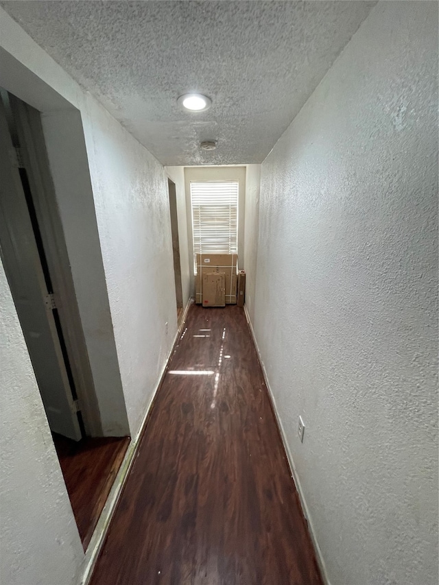 corridor with a textured ceiling and hardwood / wood-style flooring