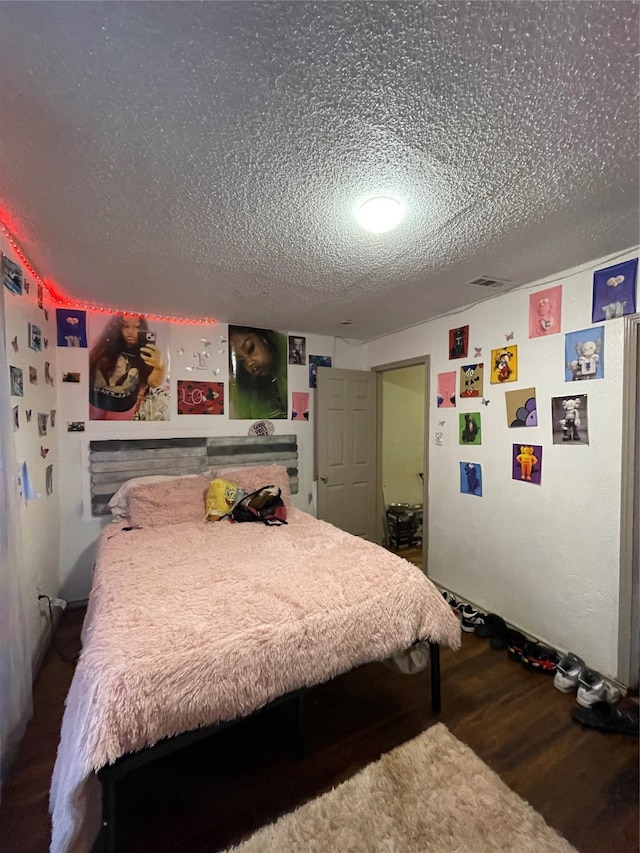 bedroom featuring a textured ceiling and dark hardwood / wood-style floors