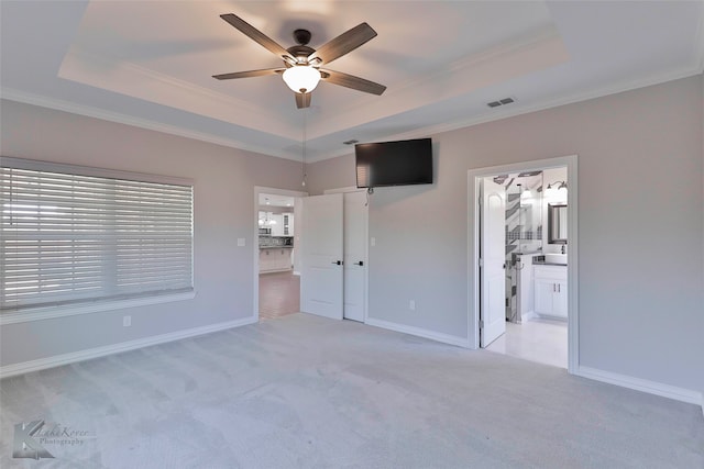 unfurnished bedroom featuring ceiling fan, a raised ceiling, and light carpet