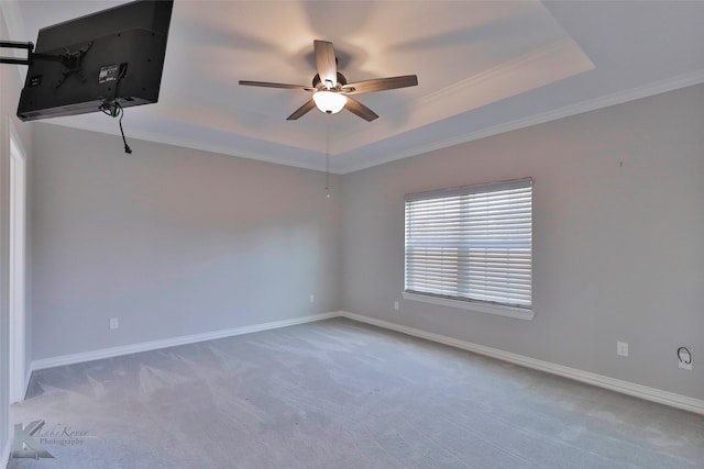 empty room featuring carpet flooring, ornamental molding, ceiling fan, and a raised ceiling