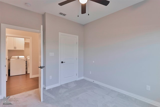 unfurnished bedroom with light hardwood / wood-style floors, washing machine and dryer, and ceiling fan