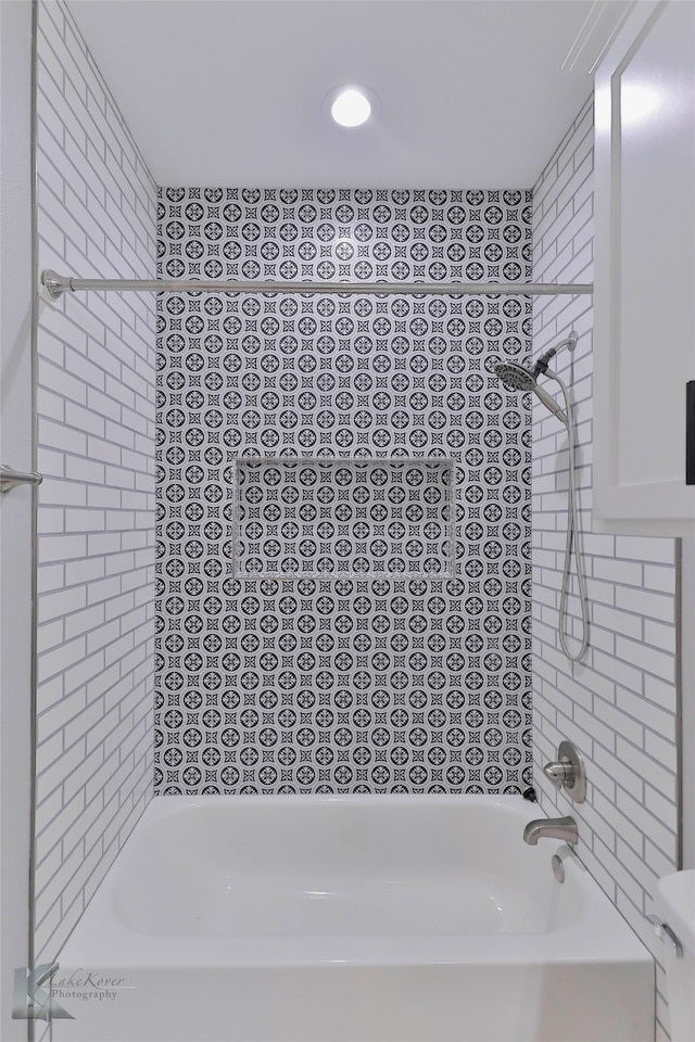 bathroom with toilet and tiled shower / bath combo