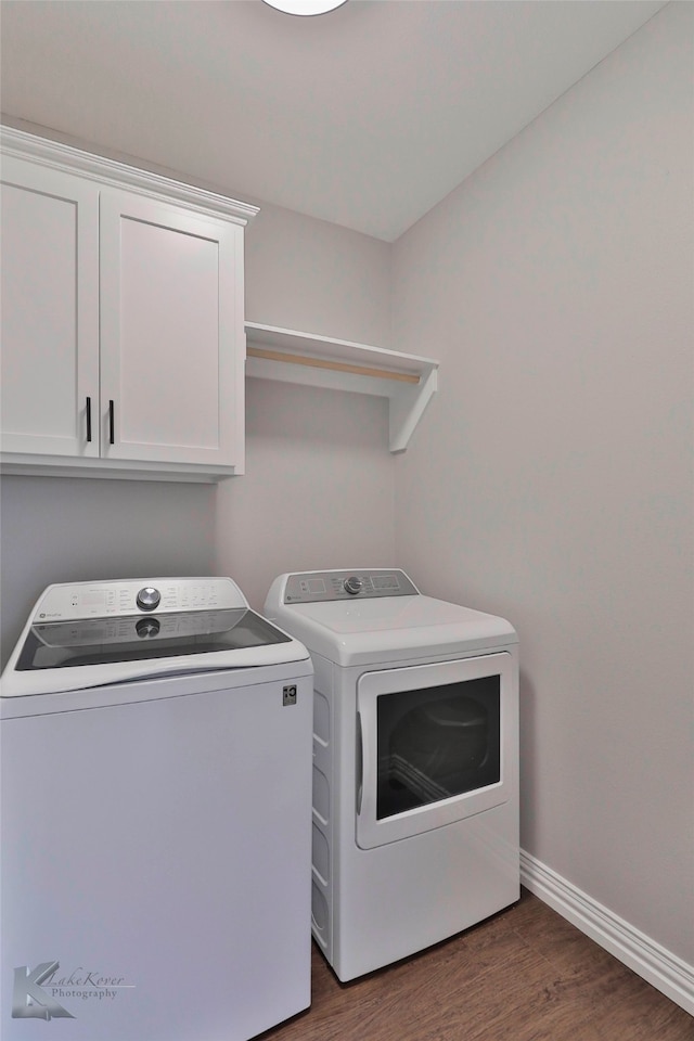 washroom featuring washer and clothes dryer, cabinets, and dark wood-type flooring