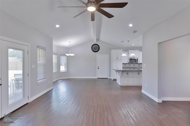 unfurnished living room with lofted ceiling with beams, ceiling fan with notable chandelier, and dark hardwood / wood-style flooring