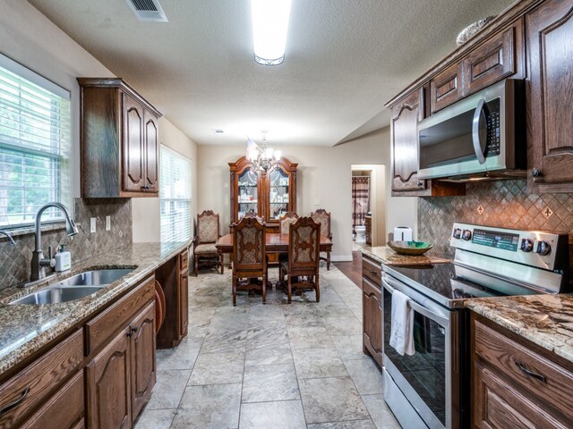 kitchen featuring sink, backsplash, light tile floors, and stainless steel appliances