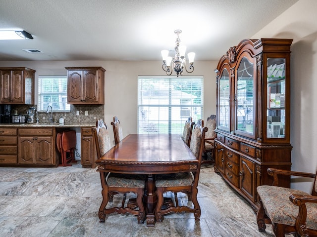 tiled dining space with sink, a chandelier, and a textured ceiling