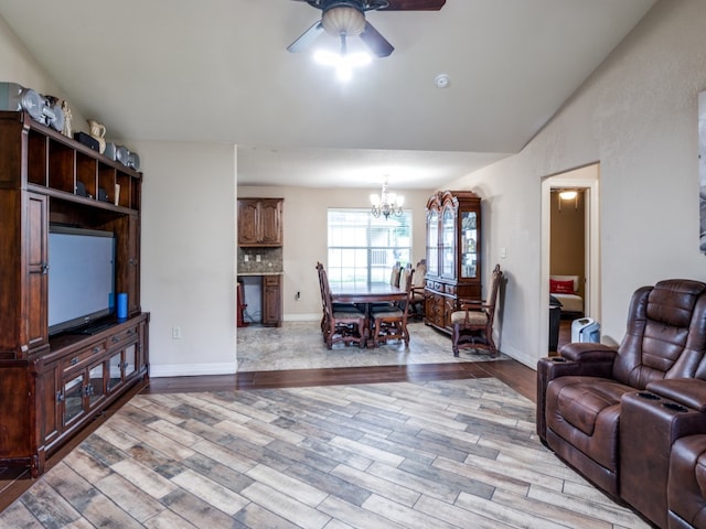 living room featuring vaulted ceiling, hardwood / wood-style flooring, and ceiling fan with notable chandelier