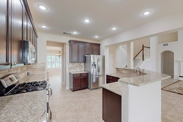 kitchen with light stone counters, tasteful backsplash, a breakfast bar area, stainless steel appliances, and dark brown cabinets