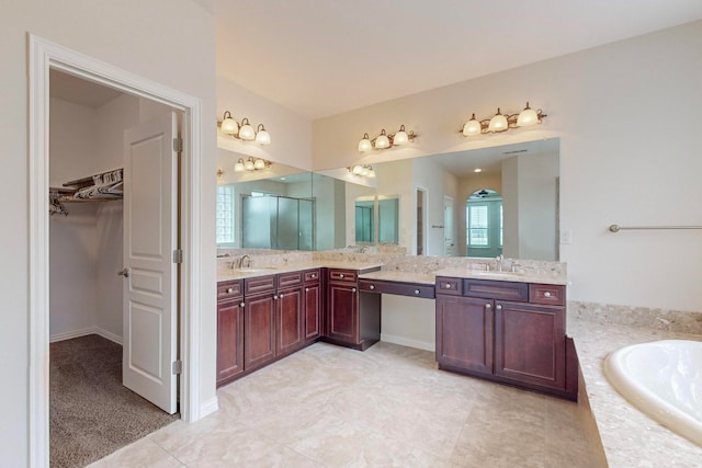 bathroom featuring a relaxing tiled tub, vanity, and tile patterned flooring