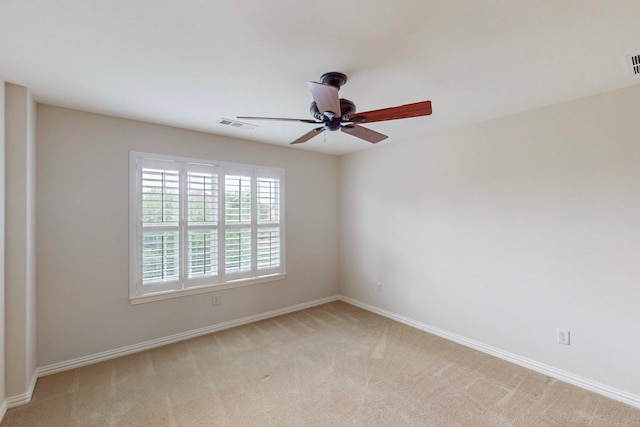 spare room with ceiling fan and light colored carpet