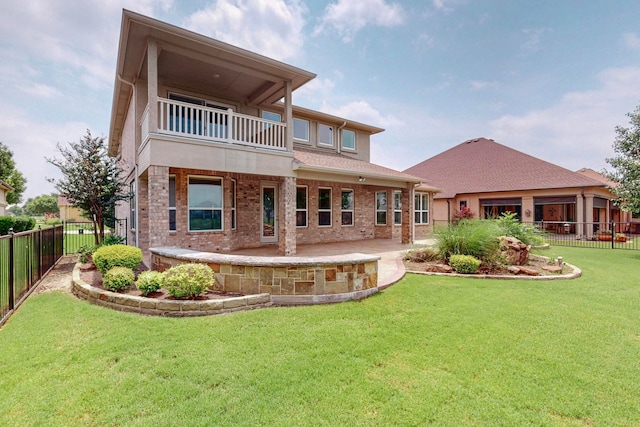 rear view of property with a balcony, a patio area, and a lawn