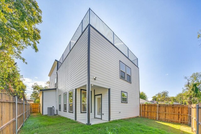 back of property featuring a lawn and central air condition unit