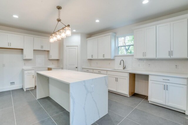 kitchen featuring decorative light fixtures, a center island, sink, and white cabinets