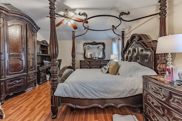 bedroom with a textured ceiling, light hardwood / wood-style floors, lofted ceiling, and ceiling fan