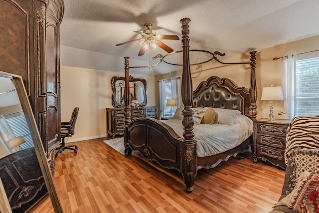 bedroom featuring light hardwood / wood-style floors, ceiling fan, multiple windows, and a textured ceiling