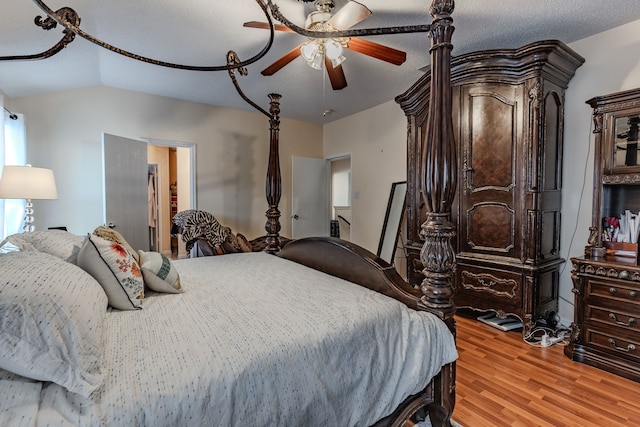 bedroom with ceiling fan, a textured ceiling, light hardwood / wood-style flooring, and lofted ceiling